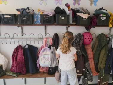 Skolebarn står med ryggen til i en garderobe med børnetøj 